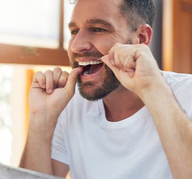 Man smiling while flossing his teeth