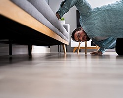 Man looking under couch at home