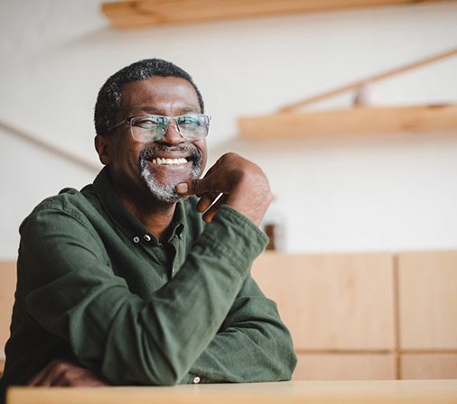 a smiling man with his chin resting on his hand